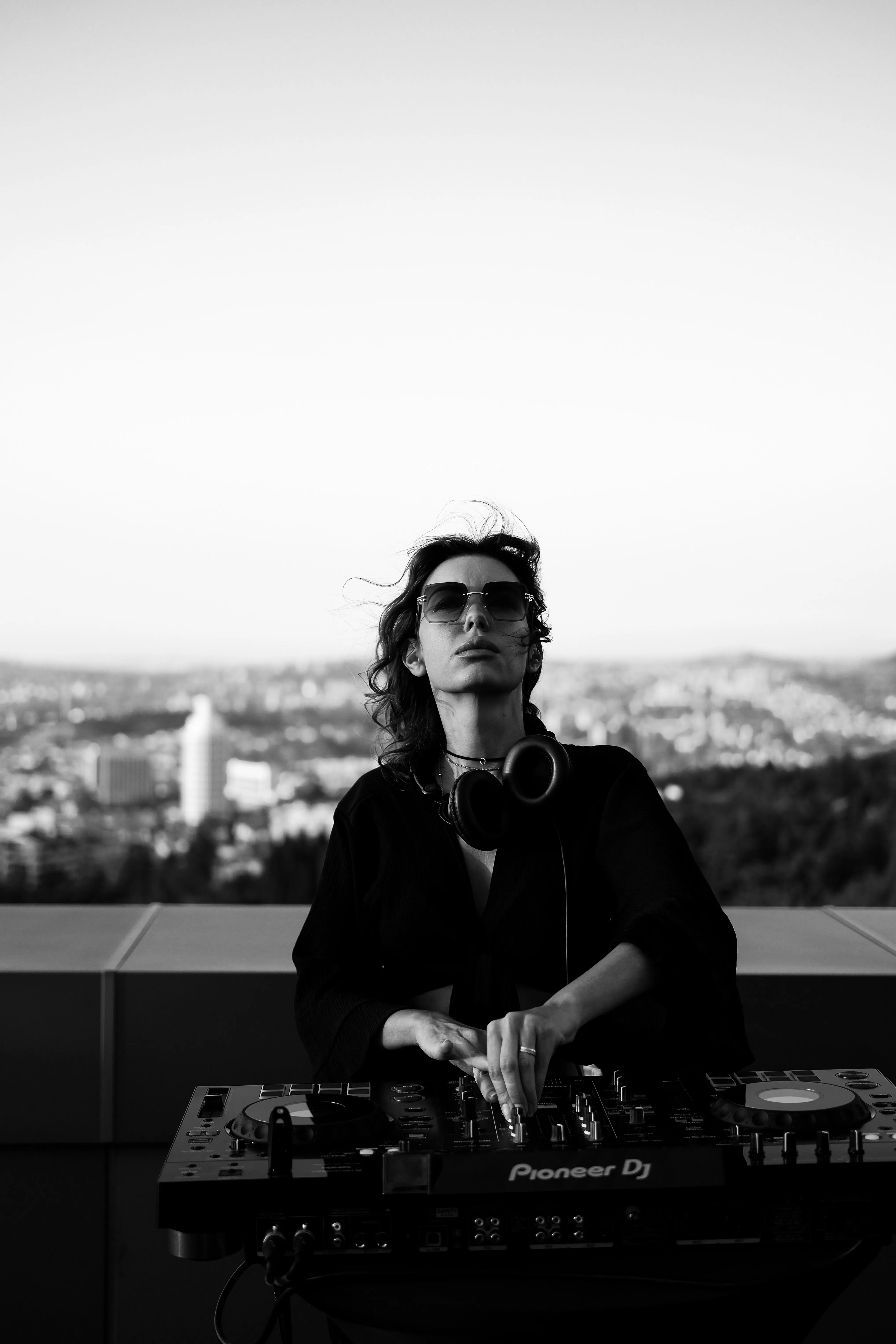 A DJ at a controller on a rooftop above the city