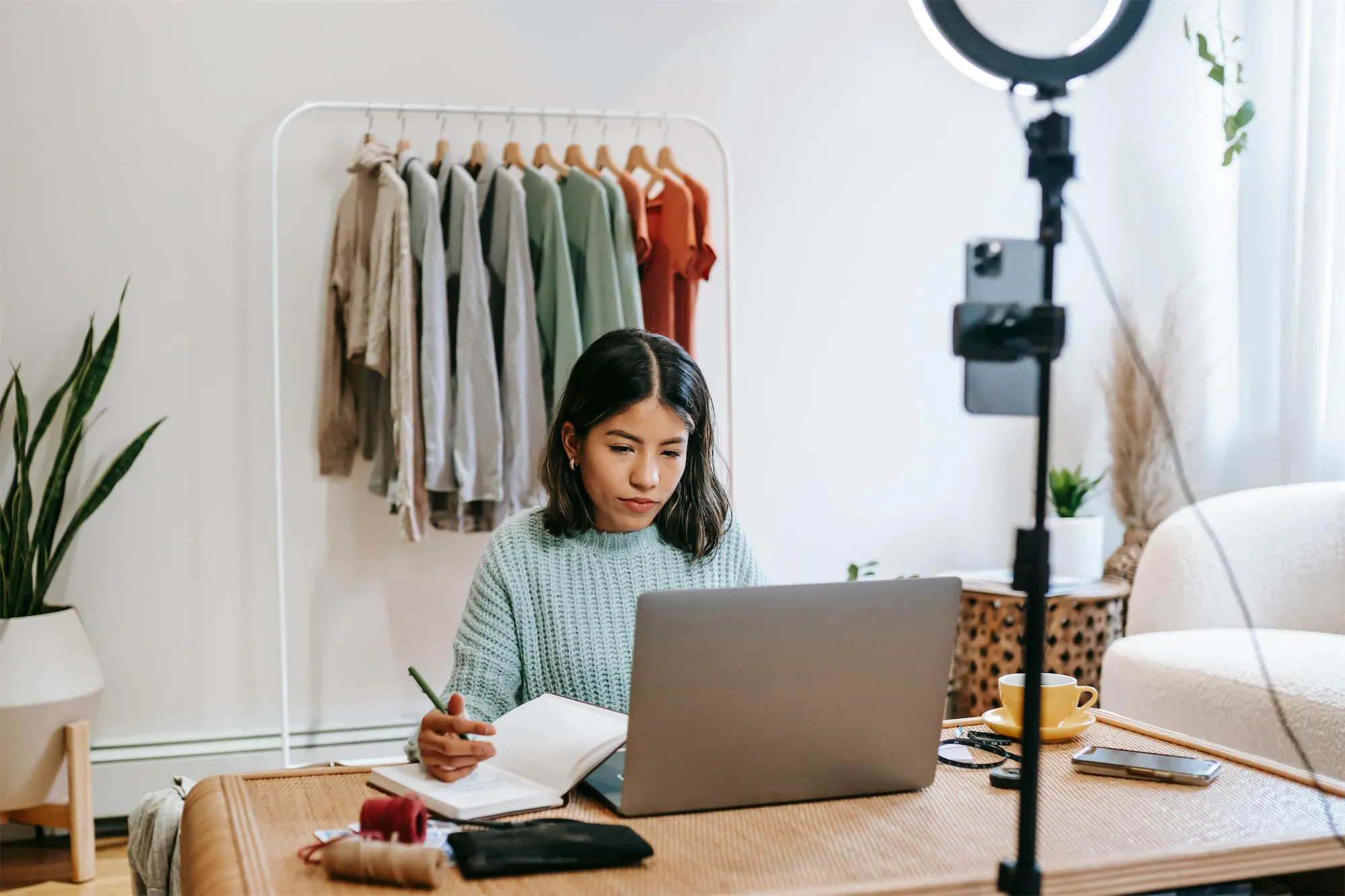 A creator working at a laptop beside a ring light and phone rig