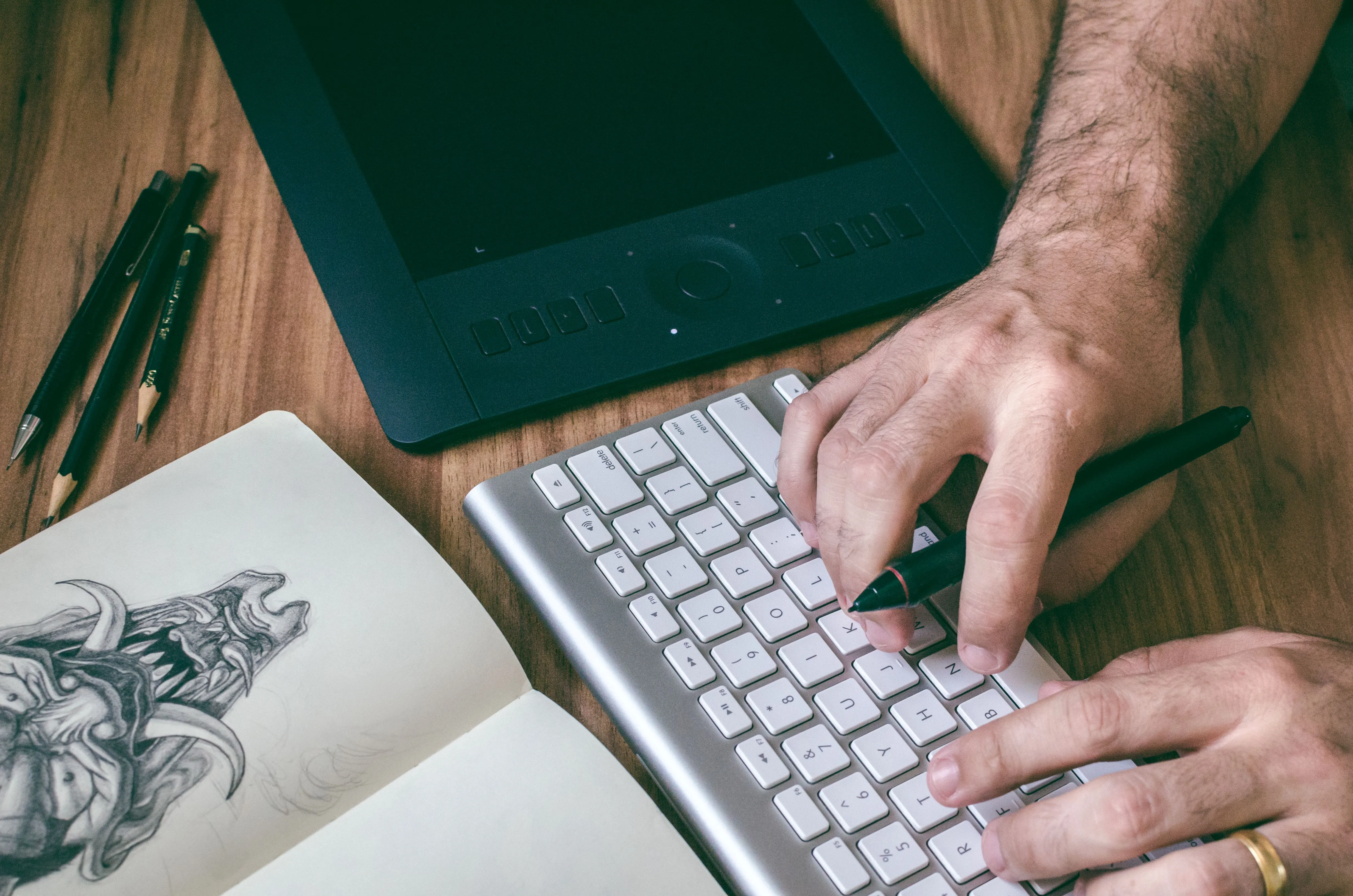 An illustrator’s desk with a sketchbook, tablet and keyboard